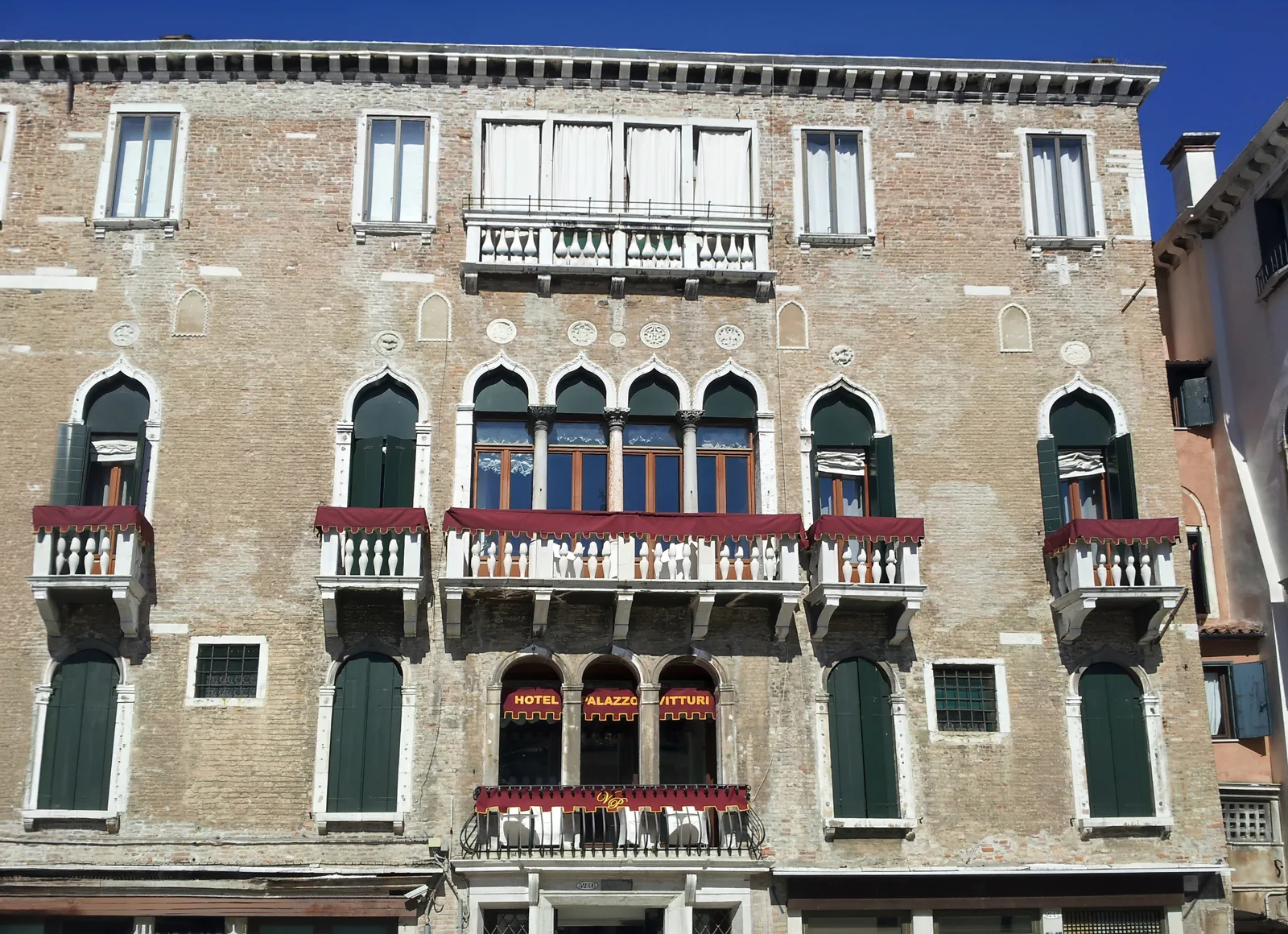 The gothic facade of Palazzo Vitturi with red awnings in daylight